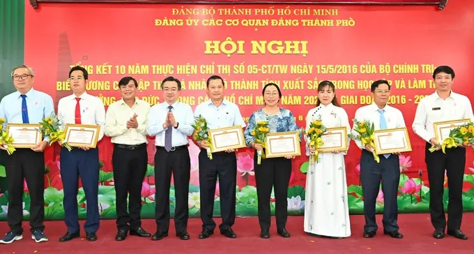Phó Bí thư Thường trực Thành ủy TPHCM Nguyễn Thanh Nghị cùng Phó Trưởng Ban Tuyên giáo và Dân vận Thành ủy TPHCM Tăng Hữu Phong chúc mừng các tập thể điển hình học và làm theo Bác năm 2025. (Ảnh: SGGP)