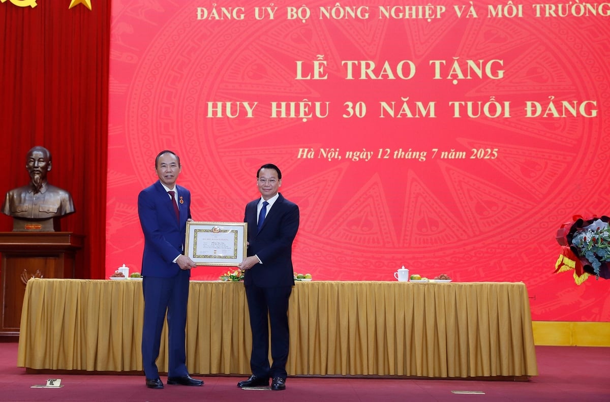 Bộ trưởng Bộ Nông nghiệp và Môi trường Đỗ Đức Duy chúc mừng Thứ trưởng Phùng Đức Tiến và khẳng định đây không chỉ là niềm tự hào của cá nhân đồng chí Tiến mà còn là vinh dự chung của toàn ngành nông nghiệp và môi trường, nơi đồng chí đã dành trọn tâm huyết và trí tuệ trong suốt sự nghiệp của mình. Ảnh: Khương Trung.